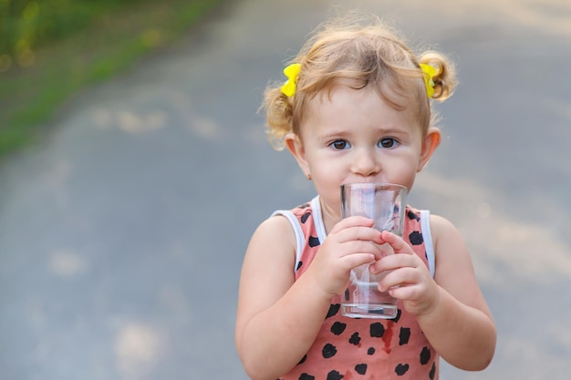 子供はグラスから水を飲む選択的な焦点