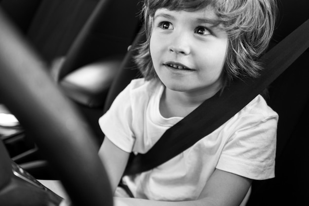 子ドライバー。ドライバーとして車を運転しながらかわいい男の子。座席に座っている赤ちゃんの子供。
