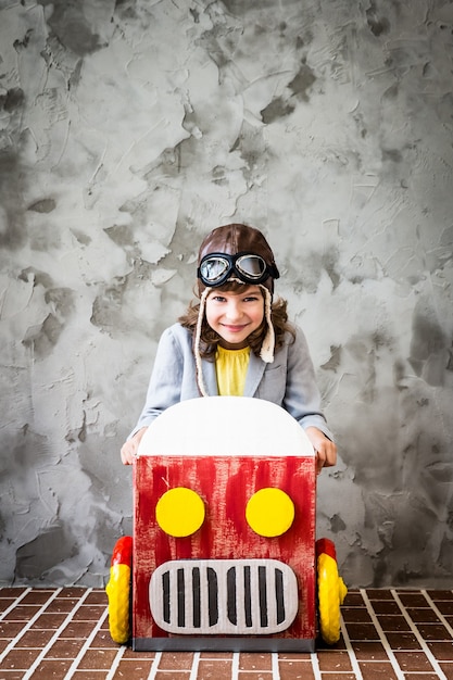 段ボール箱で作られた車を運転している子供。家で楽しんでいる子供。旅行と休暇のコンセプト