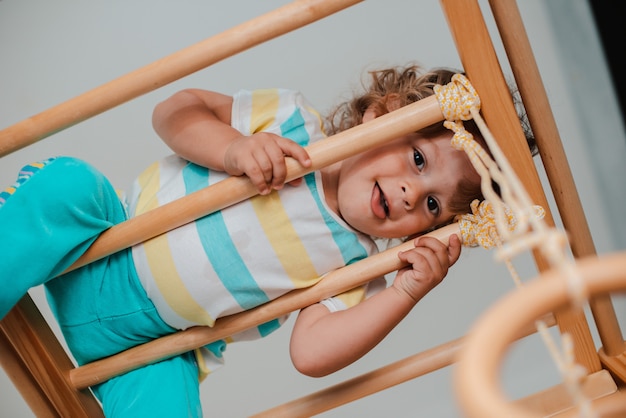 Child at an early age of 1.5 years is engaged in the home children's wooden sports complex.