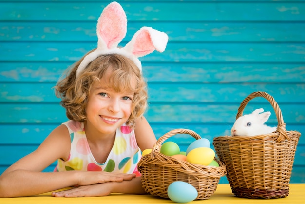 Child and Easter bunny. Kid playing with rabbit and eggs