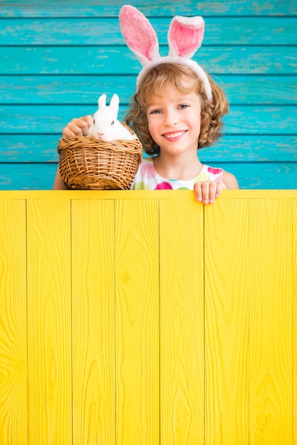 Child and easter bunny over wooden fence. kid playing with rabbit