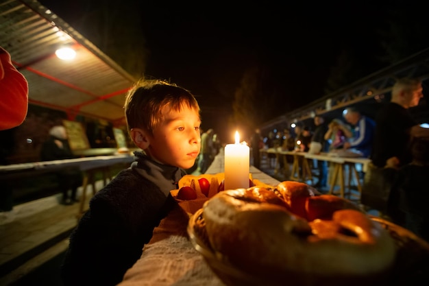 教会の庭でロールパンとキャンドルを持つイースターの夜の子供