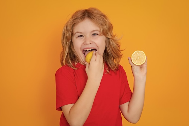 Photo child eat lemon in studio studio portrait of cute kid boy lick lemon isolated on yellow