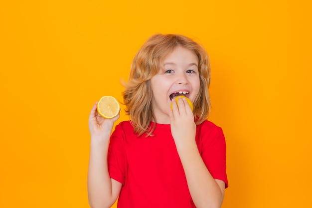 Child eat lemon in studio Studio portrait of cute kid boy lick lemon isolated on yellow