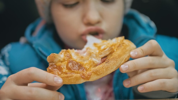 Child eat pizza cheese four Close up of young girl woman eating pizza and chewing in outdoor restaurant Kid children hands taking piece pizza