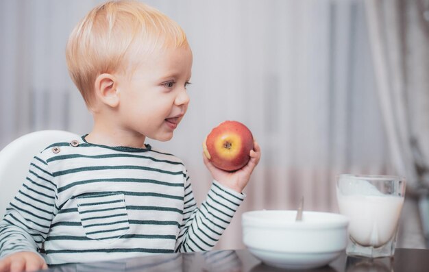 Child eat porridge kid cute boy blue eyes sit at table with plate and food healthy food boy cute bab