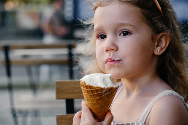 Child eating cone ice cream outside near cafe frozen summer food