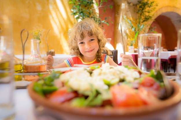 屋外の夏のカフェで食事をする子供