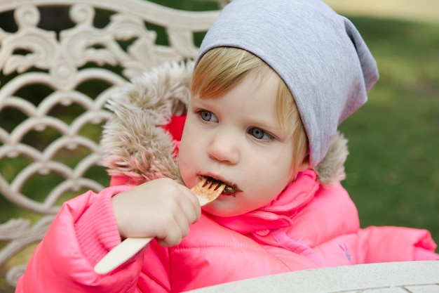 Child eating waffles with chocolate in park