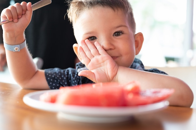 Photo child eating watermelon in a restaurant.