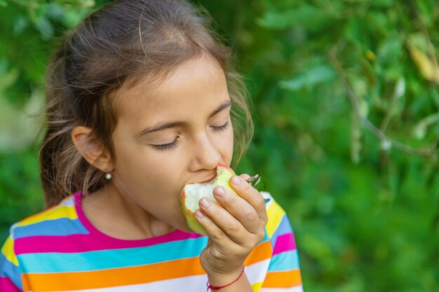 The child eats an apple in the garden. Selective focus. Kid.