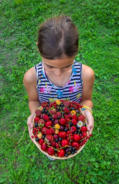 子供は庭でベリーを食べる選択的な焦点