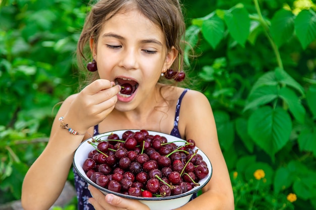 子供は庭の背景でさくらんぼを食べる