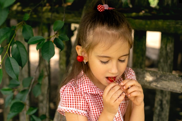 子供は目を閉じてさくらんぼを食べる木から摘み取られた熟した新鮮なジューシーなベリー