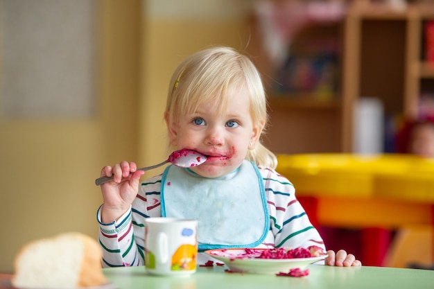 The child eats healthy food in kindergarten or at home and gets dirty