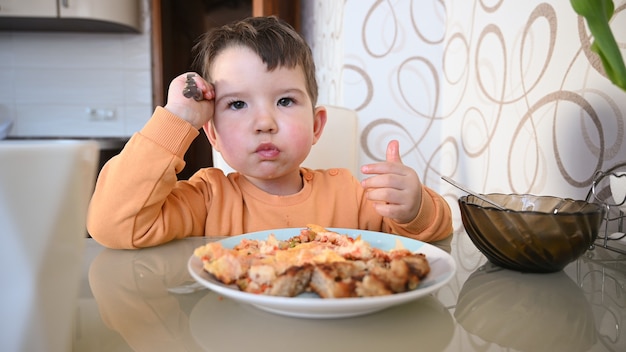 Photo the child eats on his own at the table