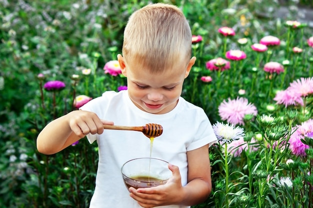 A child eats honey in a flower garden. Selective focus