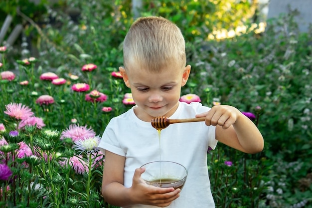 A child eats honey in a flower garden. Selective focus