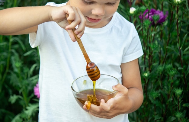 Child eats honey in the garden.