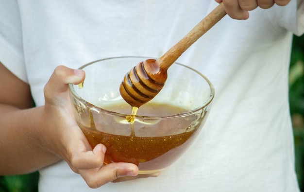 Child eats honey in the garden.