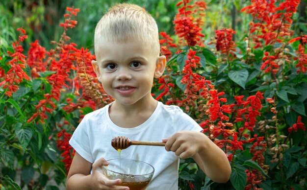 Ребенок ест мед в саду.