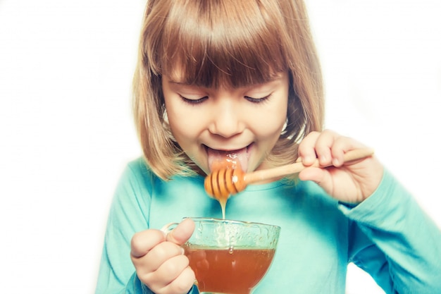 子供は蜂蜜を食べる。セレクティブフォーカス自然