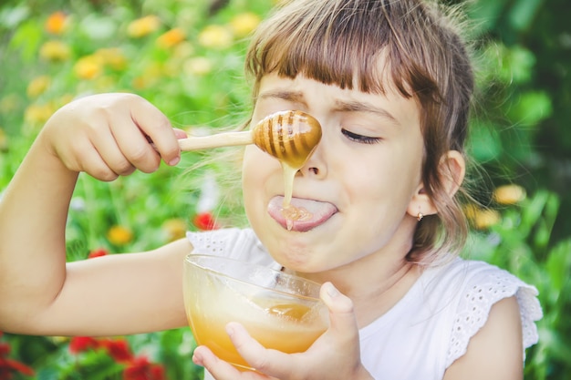 子供は蜂蜜を食べる。セレクティブフォーカス自然。