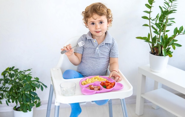 The child eats pasta and vegetables Selective focus