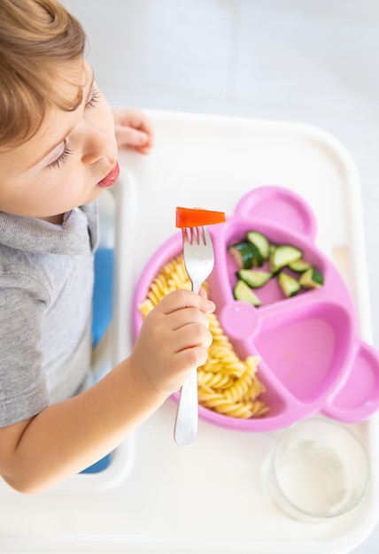 The child eats pasta and vegetables Selective focus