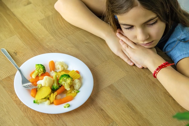 Foto il bambino mangia verdure su una sedia messa a fuoco selettiva