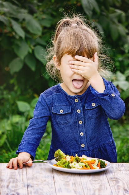 Foto il bambino mangia le verdure foto d'estate messa a fuoco selettiva