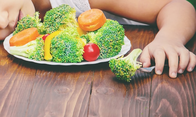 Child eats vegetables. Summer photo. Selective focus. 