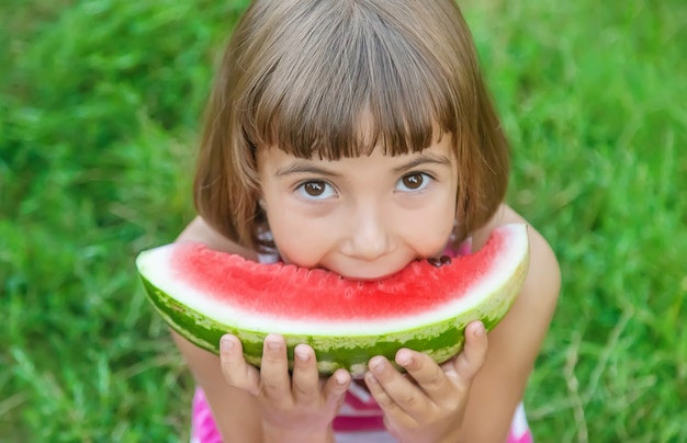 Child eats a watermelon in the garden