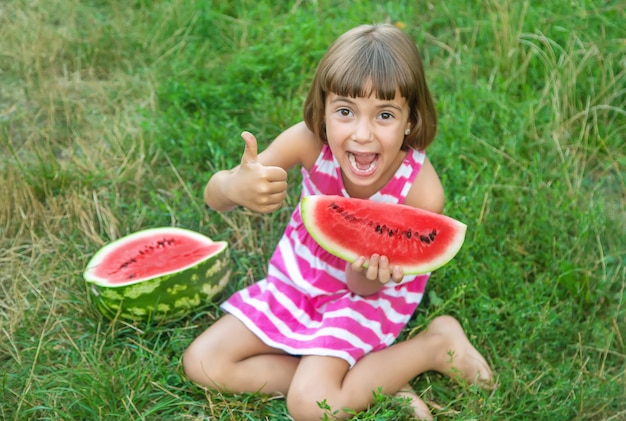 Child eats a watermelon in the garden