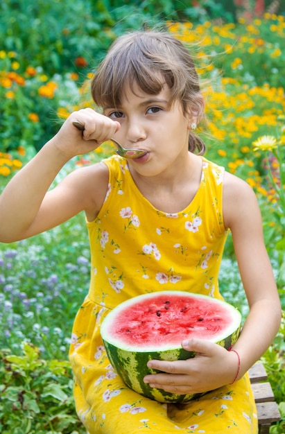 The child eats a watermelon with a spoon