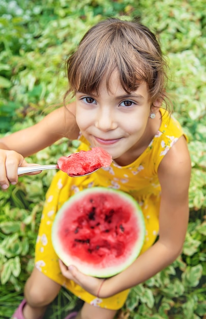 The child eats a watermelon with a spoon