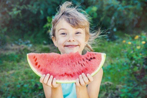 Un bambino mangia l'anguria.