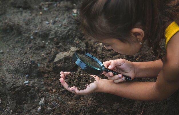 子供は虫眼鏡で地面を調べます。セレクティブフォーカス。