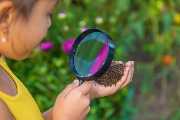 子供は虫眼鏡で地面を調べます。セレクティブフォーカス。