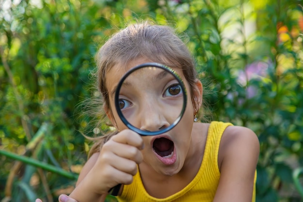 The child examines the plants with a magnifying glass. Selective focus.