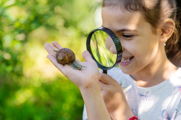 子供は木の上のカタツムリを調べます選択的な焦点