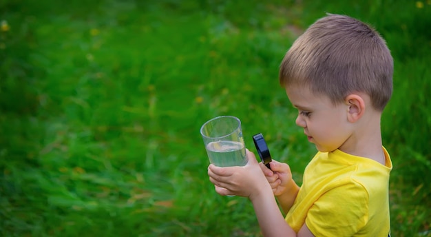 子供はガラスの拡大鏡で水を調べます選択的な焦点