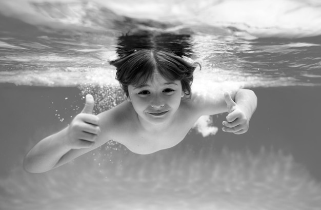 Photo child face underwater with thumbs up summer kids portrait in sea water on beach child swim and dive underwater in the swimming pool active healthy holiday