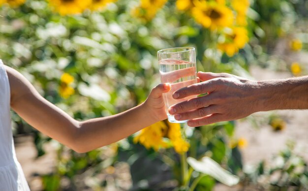 The child and the father are drinking and giving water in a glass. Selective focus.