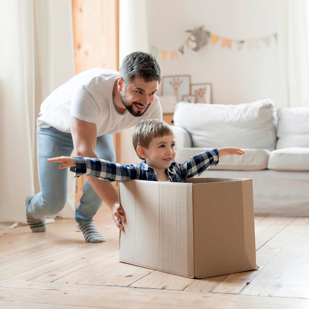 Child and father playing with a box in the living room