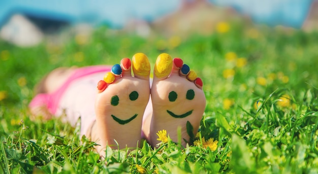 Child feet on the grass drawing a smile