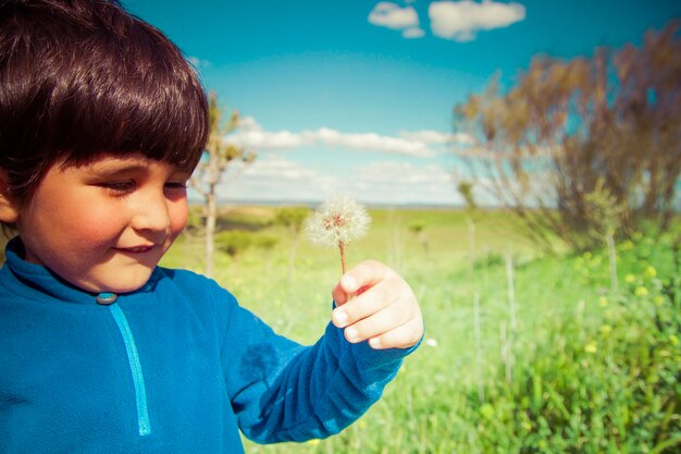 child in a field blowing a dandelion