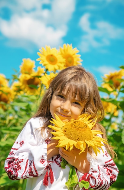 Un bambino in un campo di girasoli in una camicia ricamata.