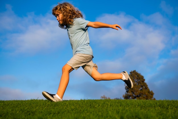 Child fun run outdoors. Kid playing in summer park. Little boy running on green fresh grass field.